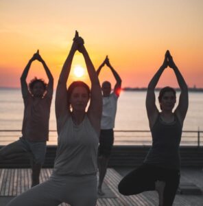 A picture showing people doing yoga at sunset - Navigating social situations with IBS - yoga