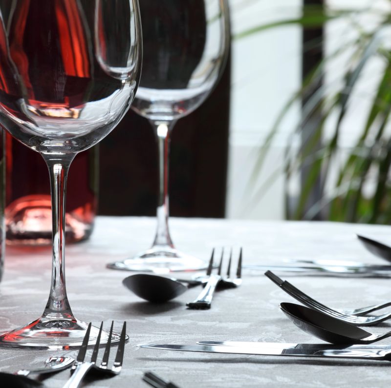 An image showing a restaurant place setting with cutlery and wine glasses