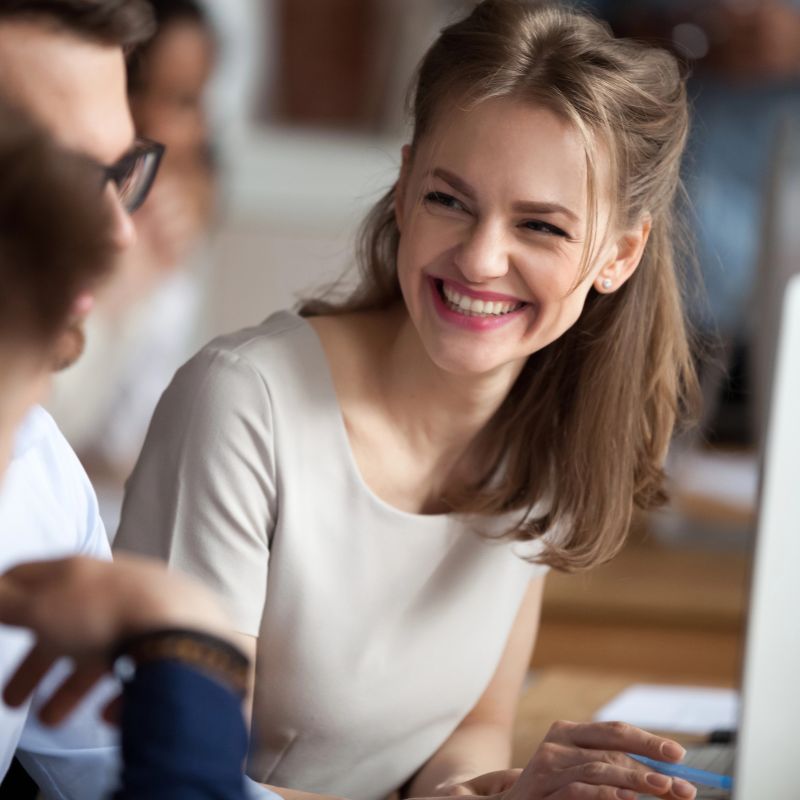 The image shows a smiling young woman conversing with colleagues, thus showing how she is coping with IBS at work