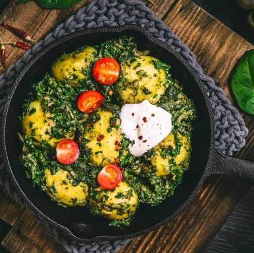 An image showing a low FODMAP Saag Aloo in a skillet on a table