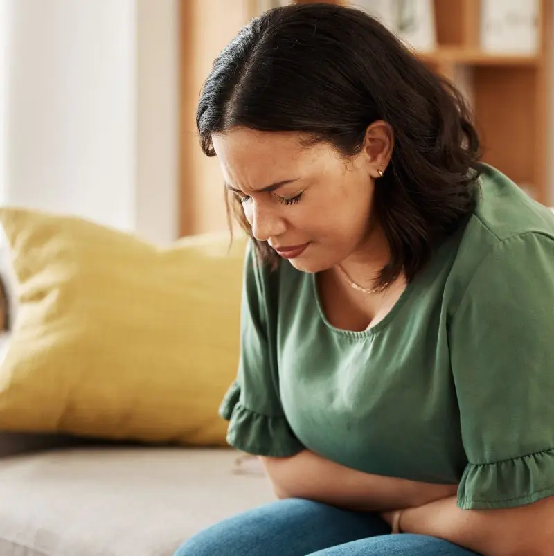 Woman experiencing IBS symptoms like bloating and stomach pain.