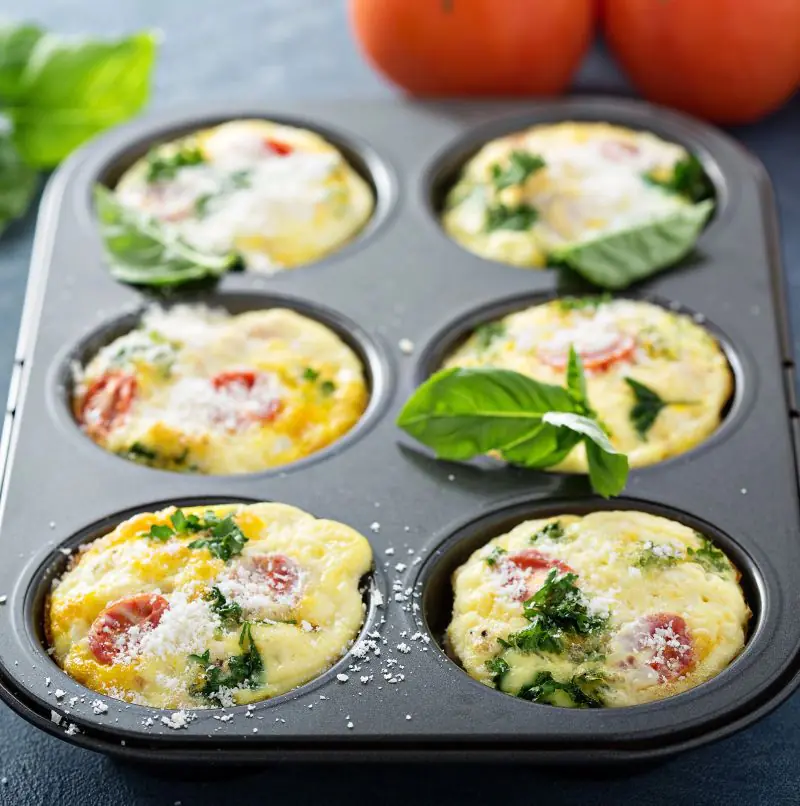The image shows a baking tray with low FODMAP Mini Frittatas and some tomatoes