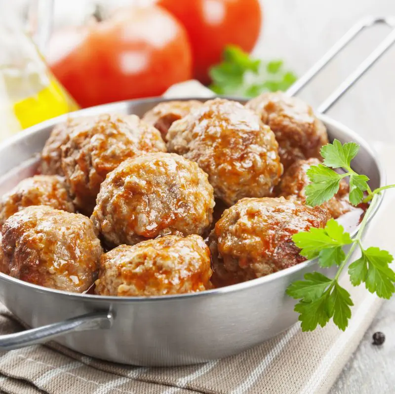 A metal dish filled with low FODMAP Lamb and Feta Meatballs, garnished with coriander