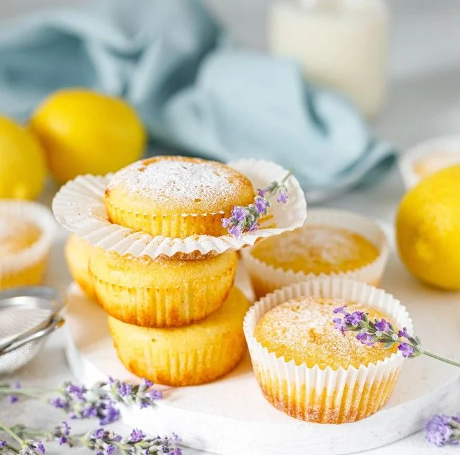 This image shows a stack of Low FODMAP Lemon Polenta Cupcakes with some lavender and a blue cloth in the background